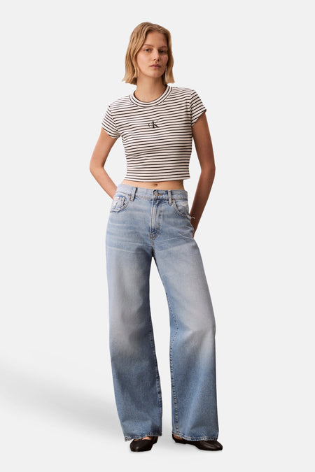 Meerkleurig T-shirt van Calvin Klein, met korte mouwen en gestreept dessin, gedragen met wijde jeans.

