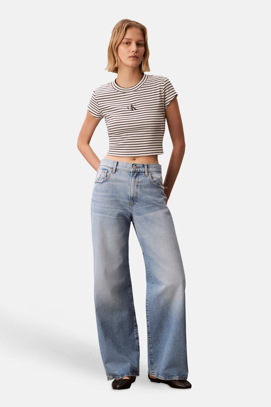 Meerkleurig T-shirt van Calvin Klein, met korte mouwen en gestreept dessin, gedragen met wijde jeans.
