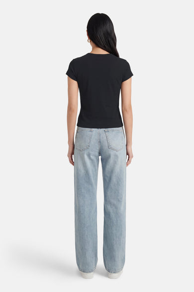 T-shirt noir à manches courtes de Calvin Klein, vu de dos, associé à un jean bleu clair et des chaussures blanches.