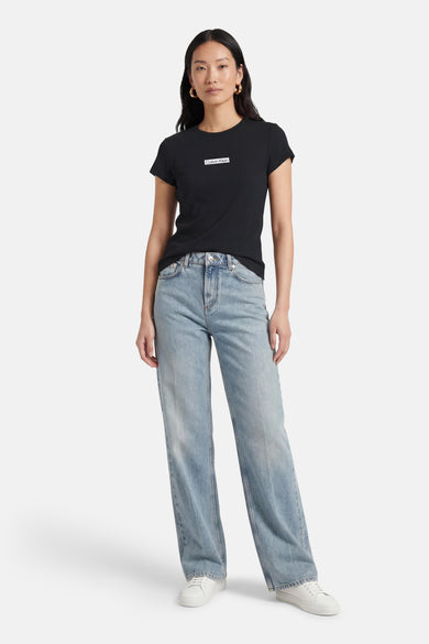 T-shirt noir à manches courtes de Calvin Klein, porté avec un jean bleu et des baskets blanches.
