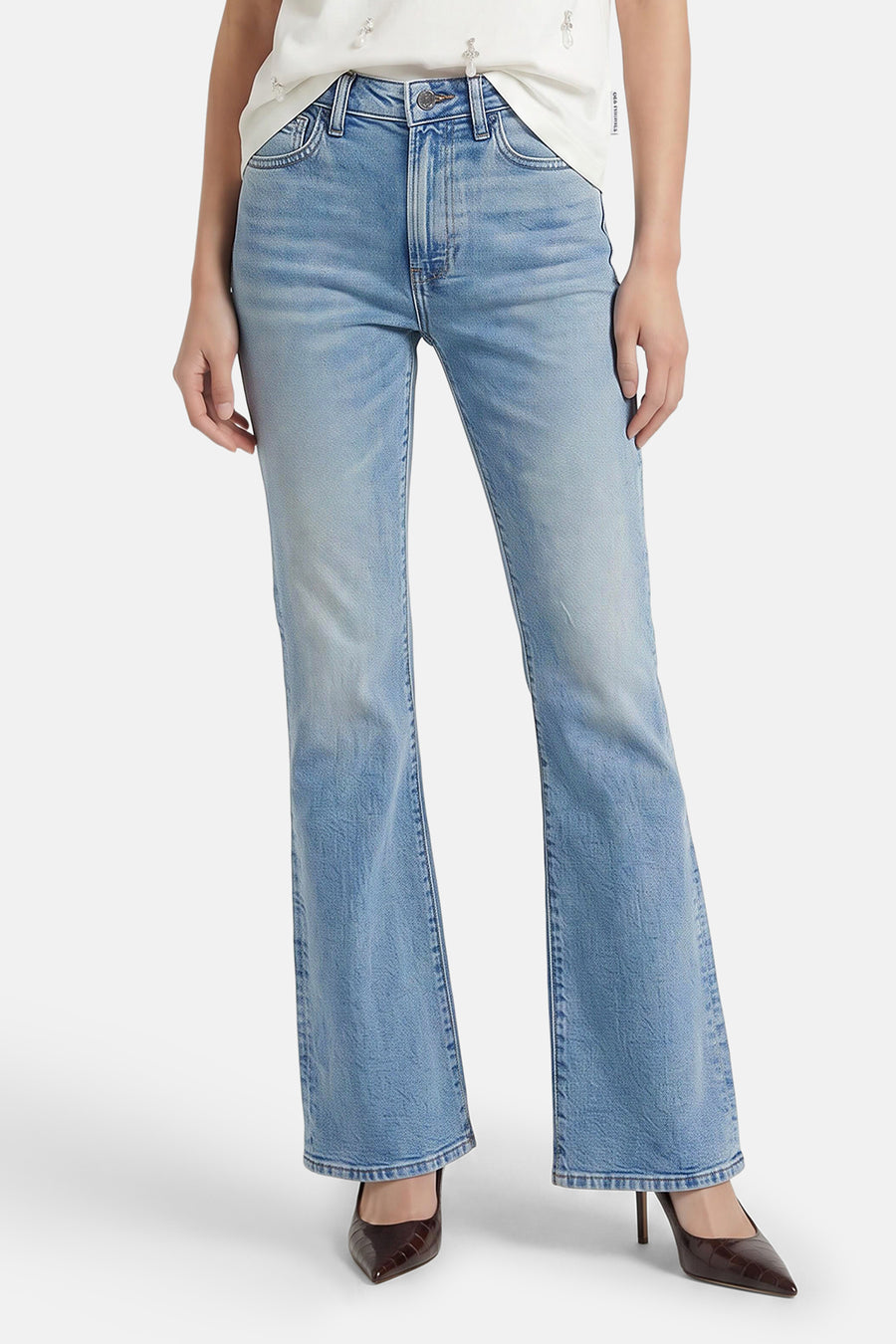 Lichtblauwe skinny bootcut jeans van Calvin Klein, met verbleekt denim, strakke pasvorm en wijde pijpen, gedragen met een wit topje en bruine hakken.