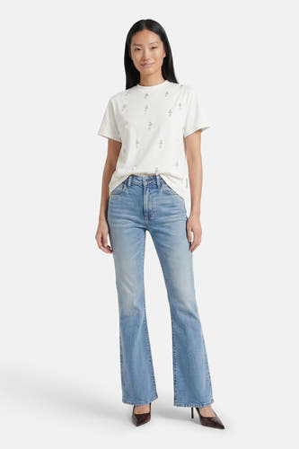 Lichtblauwe skinny bootcut jeans van Calvin Klein, met verbleekt denim, strakke pasvorm en flared pijpen, gedragen met een witte t-shirt en bruine hakken.