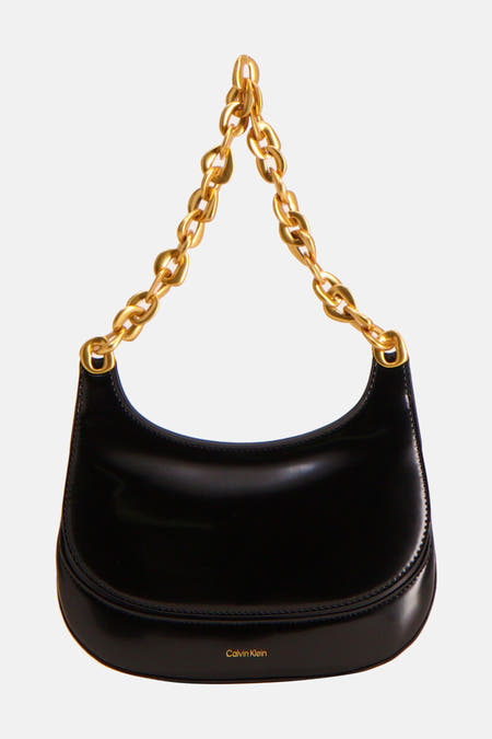 Zwarte schoudertas van Calvin Klein met een goudkleurige schakelketting als hengsel.

