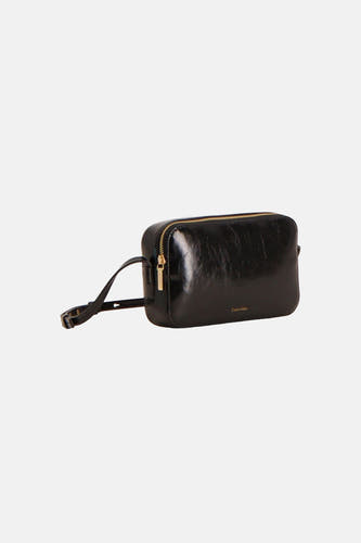 Zwarte glanzende schoudertas van Calvin Klein met goudkleurige rits, verstelbare riem en klein logo, schuin gepresenteerd.