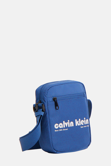Sac à dos bleu de Calvin Klein avec logo blanc imprimé et fermeture éclair noire.