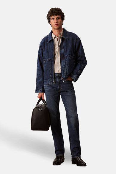 Donkerblauwe rechte jeans van Calvin Klein, gecombineerd met een blauw denim jasje en leren tas.
