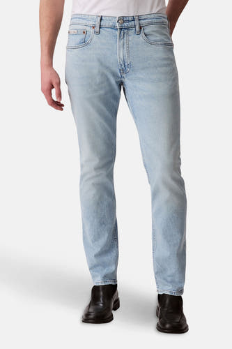 Slim fit jeans van lichtblauw denim van Calvin Klein, met traditionele vijfzakkenstyling en zwarte schoenen.
