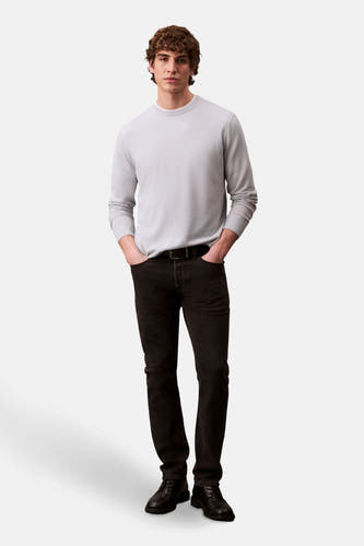 Zwarte slim fit jeans van Calvin Klein, gedragen met een lichtgrijze trui en zwarte schoenen.
