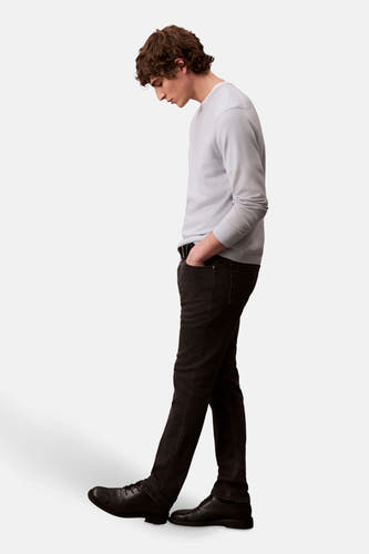 Zwarte slim fit jeans denim van Calvin Klein, staand model in zij-aanzicht met handen in de zakken.
