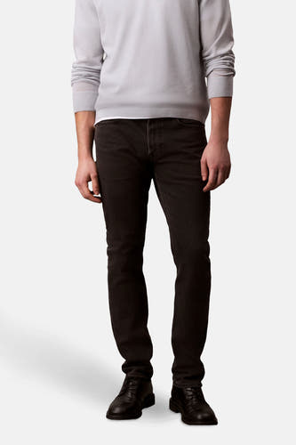 Zwarte slim jeans van Calvin Klein, gedragen met een lichtgrijze trui en zwarte leren schoenen.
