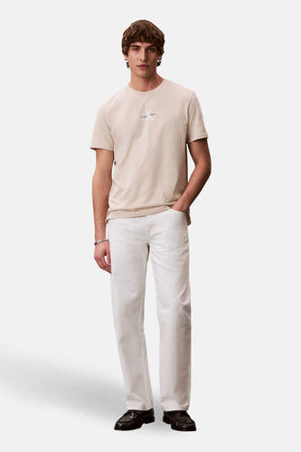 T-shirt écru à manches courtes de Calvin Klein, porté avec un jean blanc et des mocassins noirs.