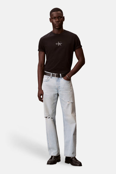 Zwart T-shirt met korte mouwen van Calvin Klein, met subtiel logo en omgeslagen mouwen, gedragen door een man met lichte distressed jeans.