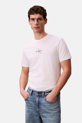 T-shirt blanc à manches courtes Calvin Klein, avec un logo CK gris sur la poitrine, porté par un homme en jean bleu clair.