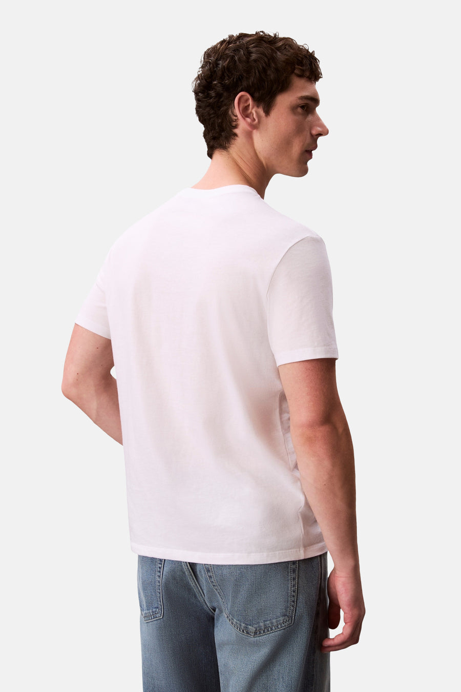 T-shirt blanc à manches courtes Calvin Klein, photographié de dos et de côté sur un homme portant un jean.