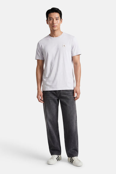 Grijze korte mouw T-shirt van Calvin Klein met klein logo op borst, gedragen met donkere jeans en witte sneakers, front view