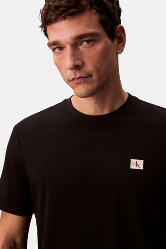 T-shirt noir à manches courtes de Calvin Klein, avec un patch logo sur la poitrine.