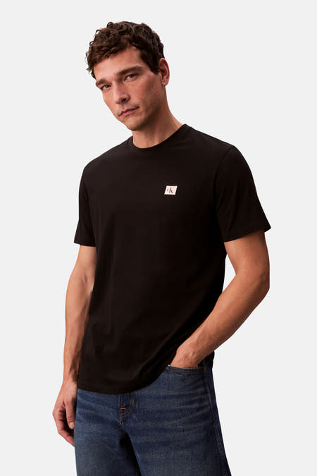 Zwart T-shirt met korte mouwen van Calvin Klein, gedragen met een blauwe jeans en één hand in de zak.
