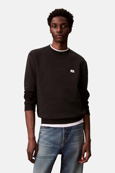 Gilet noir à col rond de Calvin Klein, avec petit logo sur la poitrine et col blanc.