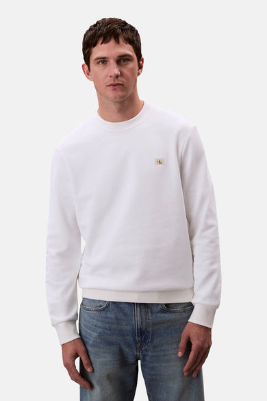 Pull-over blanc avec col rond de Calvin Klein, vu de l'arrière, associé à des jeans bleus.