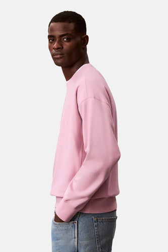 Man in roze sweater en jeans.
