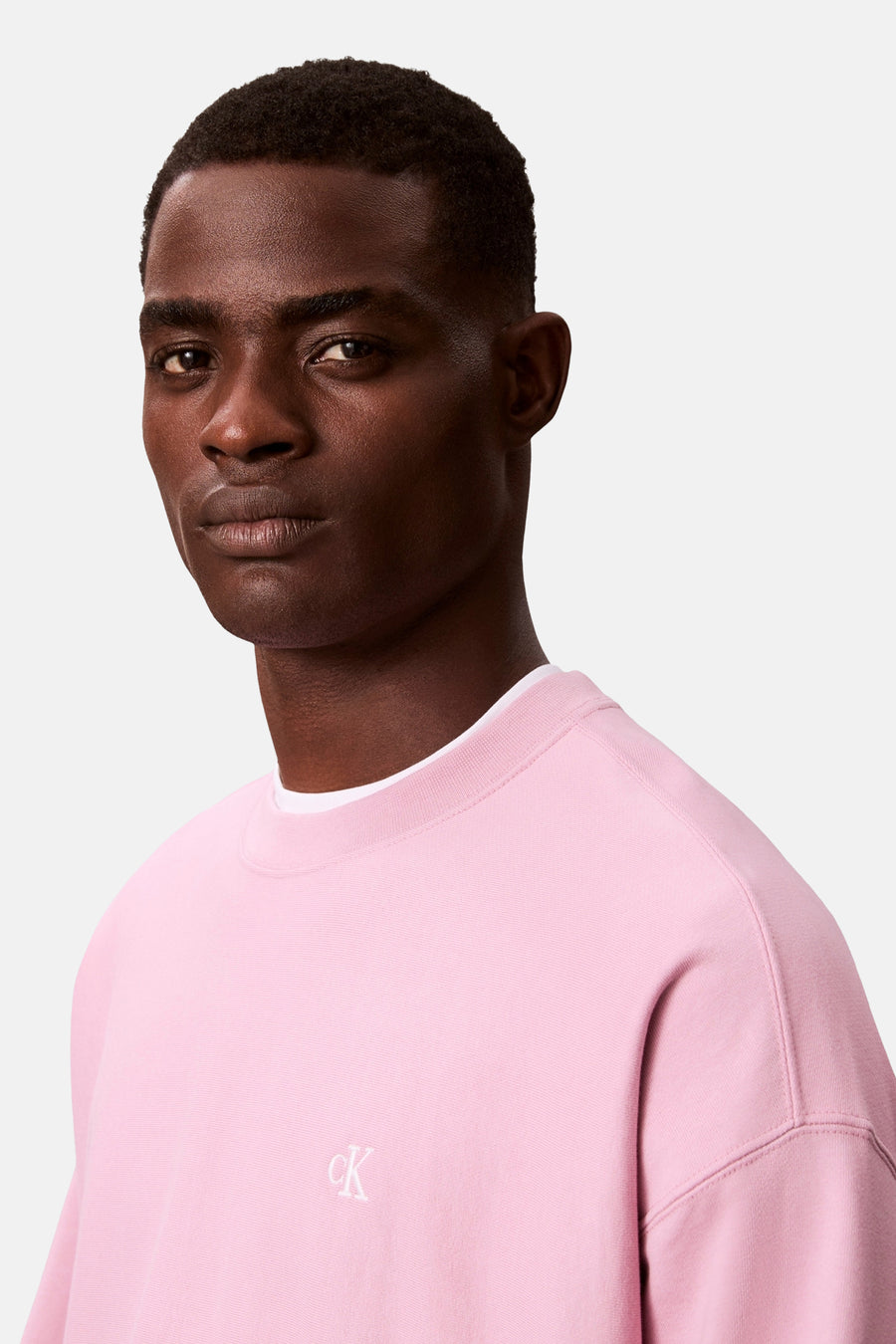 Portret van een man in een roze Calvin Klein sweatshirt.
