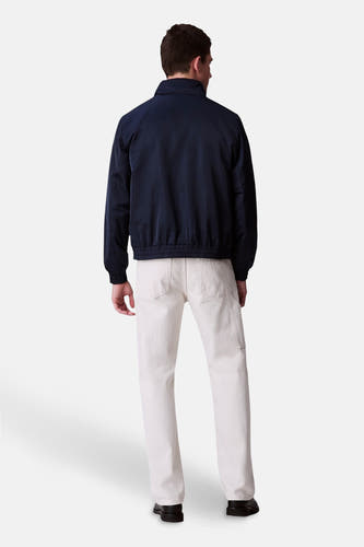 Blauwe regenjas van Calvin Klein, gezien van achteren, met een lichte broek en zwarte schoenen.