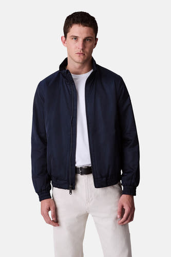 Blauwe regenjas van Calvin Klein, gedragen over een wit t-shirt en lichte broek met riem.