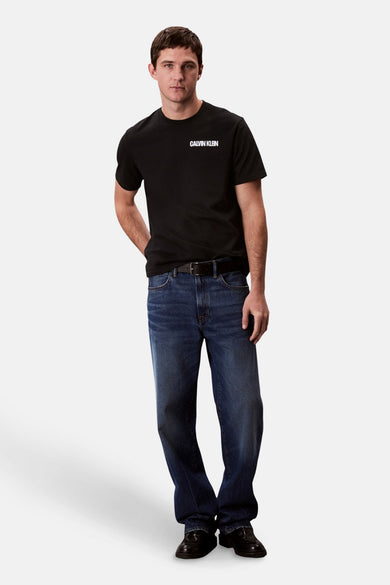 T-shirt noir à manches courtes de Calvin Klein, associé à des jeans foncés et une unece noire.
