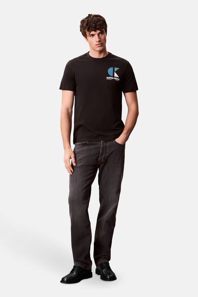 T-shirt noir à manches courtes de Calvin Klein, avec un logo sur la poitrine et porté avec des jeans foncés.