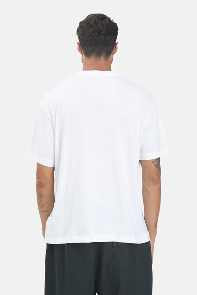 Wit T-shirt met korte mouwen van Calvin Klein, gezien vanaf de achterkant, met tatoeages op de armen en zwarte broek.