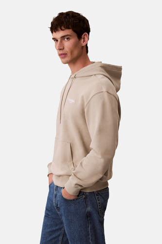 Gilet beige avec capuche de Calvin Klein Jeans, avec cordon et poche, associé à des jeans.