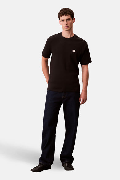 Zwart T-shirt met korte mouwen van Calvin Klein, gedragen met donkere jeans en zwarte schoenen.