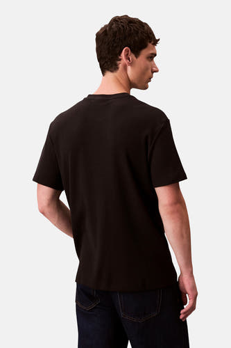 Zwart T-shirt met korte mouwen van Calvin Klein, effen textuur, achterkant van een model met jeans.
