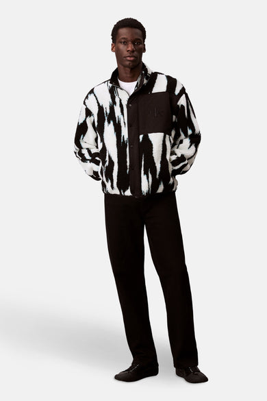 Multikleurig kort jack van Calvin Klein, met zwart-wit zebrapatroon en zwarte broek en schoenen.
