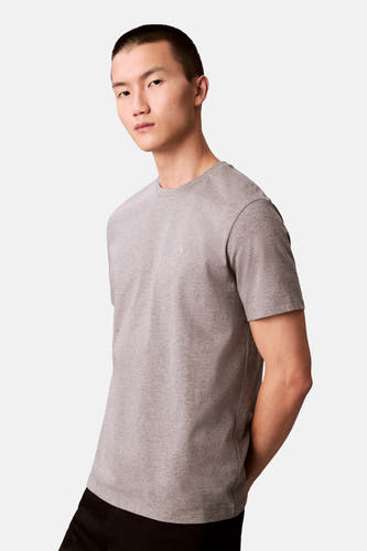 T-shirt gris à manches courtes de Calvin Klein, avec un logo discret sur la poitrine, porté avec un pantalon noir.