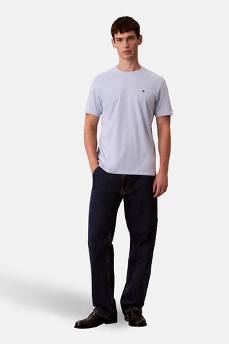 T-shirt bleu à manches courtes de Calvin Klein, porté avec des jeans foncés et des chaussures noires.