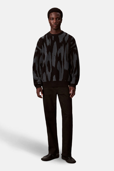 Veelkleurige trui met ronde hals van Calvin Klein, met een abstract patroon, gecombineerd met een zwarte broek en zwarte schoenen.
