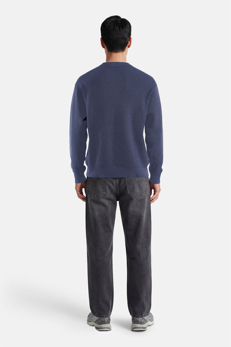 Blauwe ronde hals trui van Calvin Klein, achterzijde, fijn gebreid, gestreept patroon, gecombineerd met donkere jeans en sneakers