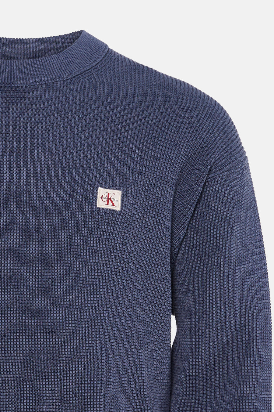 Blauwe ronde hals trui van Calvin Klein met fijne ribstructuur en klein wit logo op borst, close-up voorzijde