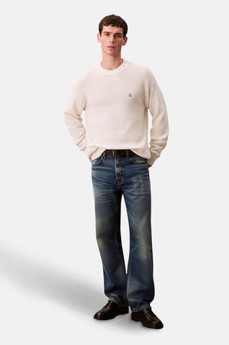 Marinière Calvin Klein avec col rond, portée avec des jeans et des chaussures noires.