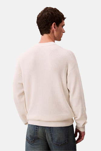 Beige trui met ronde hals van Calvin Klein, achterkant gezien, met geweven textuur en blauwe jeans.

