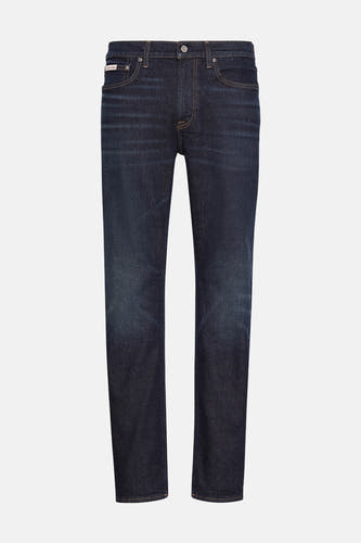Jean tapered bleu marine de Calvin Klein, avec des zones de usure subtiles et des surpiqures contrastantes.