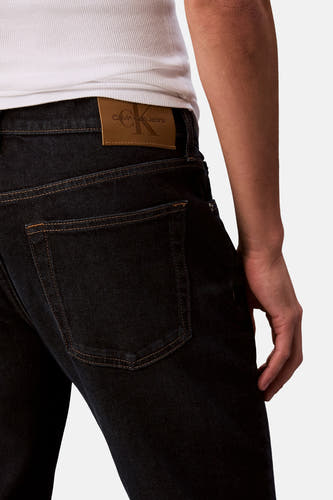 Jean tapered bleu marine de Calvin Klein Jeans, avec une étiquette en cuir sur l'arrière.