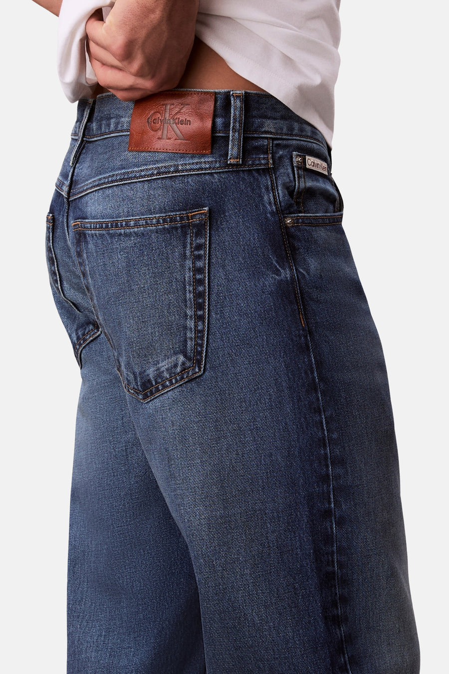 Rechte blauwe jeans van denim, van Calvin Klein, met bruin leren label en stiksels op de achterzak.
