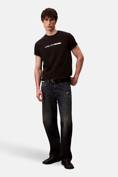 Zwart T-shirt met korte mouwen van Calvin Klein, gedragen met donkerblauwe jeans en zwarte schoenen.

