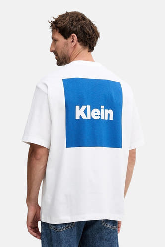 T-shirt blanc à manches courtes de Calvin Klein, avec un carré bleu et le nom de la marque sur le dos.