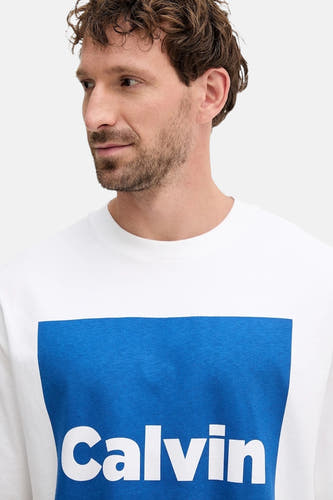 T-shirt blanc à manches courtes de Calvin Klein, avec un bloc bleu et le texte "Calvin" dessus.