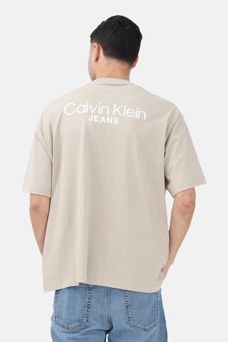 Beige T-shirt met korte mouwen van Calvin Klein Jeans, met logo op de rug en blauwe jeans.