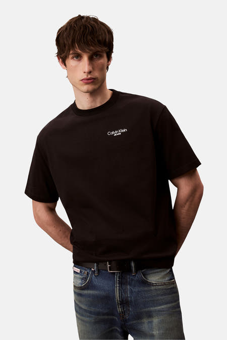 Zwart T-shirt met korte mouwen van Calvin Klein Jeans, gedragen met een blauwe jeansbroek en een zwarte riem.