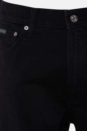 Jean droit noir de Calvin Klein, gros plan, avec boutons métalliques gravés du logo et petite étiquette en tissu sur la poche monnaie.